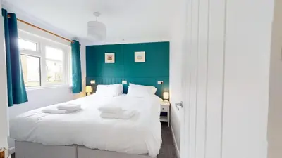 a bedroom with a large white bed with blue walls at F60 Atlantic View, Riviere Towans in Hayle