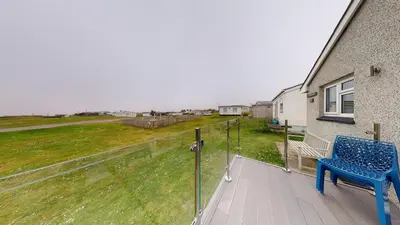 a blue chair sitting on a deck next to a house at F60 Atlantic View, Riviere Towans in Hayle