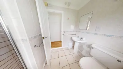 a white bathroom with a toilet and a sink at F60 Atlantic View, Riviere Towans in Hayle
