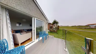 a balcony with blue chairs and a couch on a house at F60 Atlantic View, Riviere Towans in Hayle