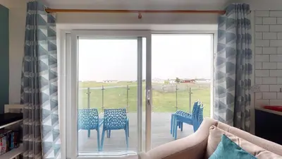 a room with a sliding glass door with chairs on a patio at F60 Atlantic View, Riviere Towans in Hayle