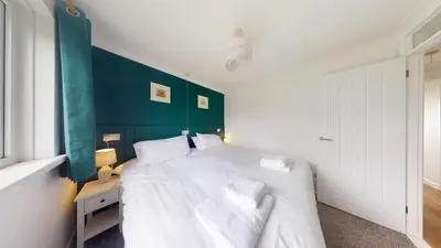 a bedroom with a white bed with a green headboard at F60 Atlantic View, Riviere Towans in Hayle