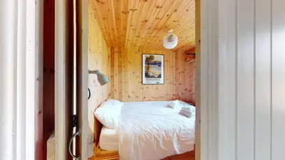a small bedroom with a bed in a wooden wall at F67 Ischia, Riviere Towans in Hayle