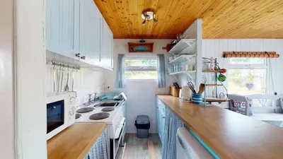 a kitchen with white cabinets and a wooden ceiling at F67 Ischia, Riviere Towans in Hayle