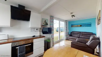 a kitchen and living room with a couch and a table at G10 Veula, Riviere Towans in Hayle