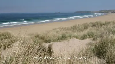 a sandy beach with grass and the ocean at G10 Veula, Riviere Towans in Hayle