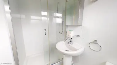 a white bathroom with a sink and a shower at G10 Veula, Riviere Towans in Hayle
