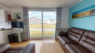 a living room with a couch and a large window at G10 Veula, Riviere Towans in Hayle