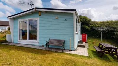a blue house with a bench and a picnic table at G10 Veula, Riviere Towans in Hayle