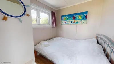 a small bedroom with a bed and a mirror at G10 Veula, Riviere Towans in Hayle