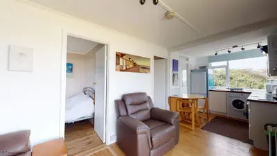 a living room with a chair and a bedroom at G10 Veula, Riviere Towans in Hayle