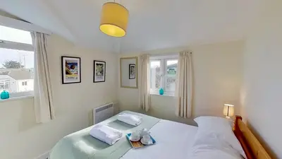 a bedroom with a bed with two pillows and a window at F18 Branksea, Riviere Towans in Hayle