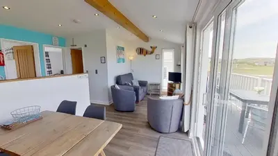 a living room with a wooden table and chairs at F55 Begondulkare, Riviere Towans in Hayle