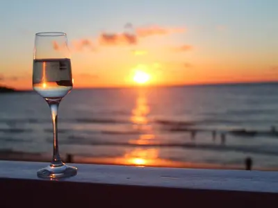 a glass of wine sitting on the beach at sunset at Louies Loft in St Ives