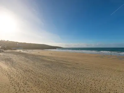 a sandy beach with people flying a kite at Louies Loft in St Ives
