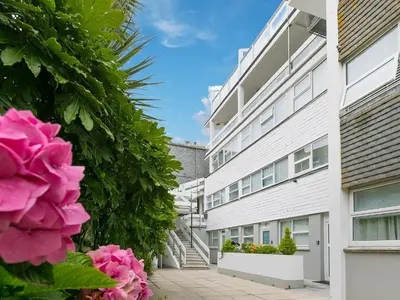 a white building with pink flowers in front of it at Louies Loft in St Ives