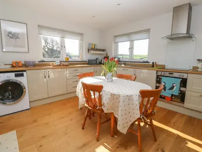 a kitchen with a table with a vase of flowers on it at Chilowan in Tintagel