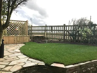 a garden with a wooden fence and green grass at Little Pityme in Wadebridge