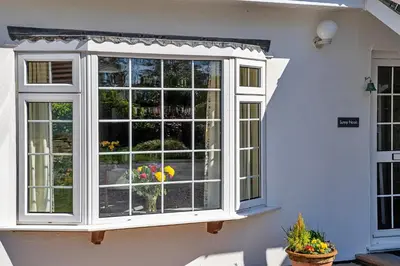 a white window on a white house with flowers at Finest Retreats - Sunny Nook in Padstow