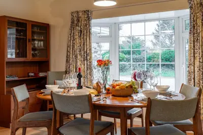 a dining room with a table and a large window at Finest Retreats - Sunny Nook in Padstow