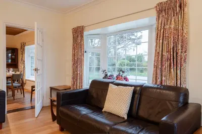a living room with a leather couch and a large window at Finest Retreats - Sunny Nook in Padstow