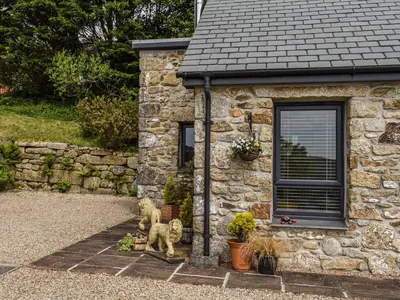 a stone house with two statues of dogs in front of it at Bolivar Barn in Gwennap