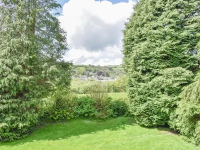 a view of a garden between two large trees at Moorside - Uk43497 in Lostwithiel