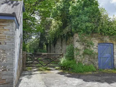 an old stone wall with a blue door and a gate at Moorside - Uk43497 in Lostwithiel