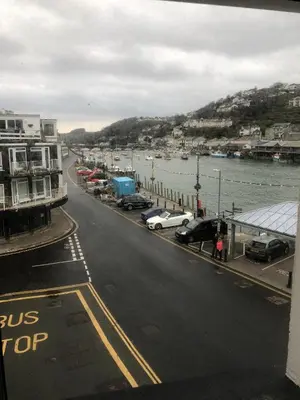 a city street with cars parked next to a body of water at 4 Quay View, Looe in Looe