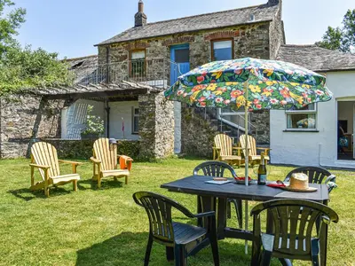 a table and chairs and an umbrella in a yard at Poundhouse - Uk43496 in Lostwithiel