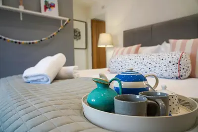 a tray of tea pots and cups on a bed at Luxury holiday cottage by the harbour in St Mawes in Saint Mawes