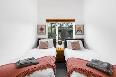 two twin beds in a room with white walls at House 5 Ironcroft - Modern Pet-friendly, Walk to beach & village in Porthtowan