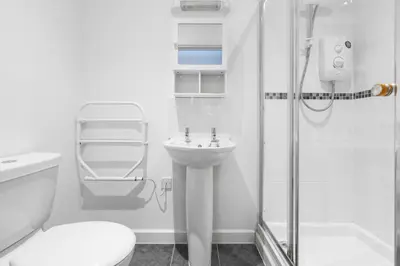 a white bathroom with a shower and a sink at House 5 Ironcroft - Modern Pet-friendly, Walk to beach & village in Porthtowan