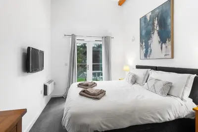 a white bedroom with a bed with towels on it at House 5 Ironcroft - Modern Pet-friendly, Walk to beach & village in Porthtowan