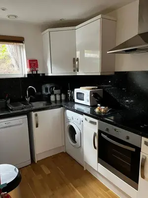 a kitchen with white cabinets and a washer and dryer at House 6 Goldcroft - Walk to Beach & Village, Pet-friendly & hottub in Porthtowan