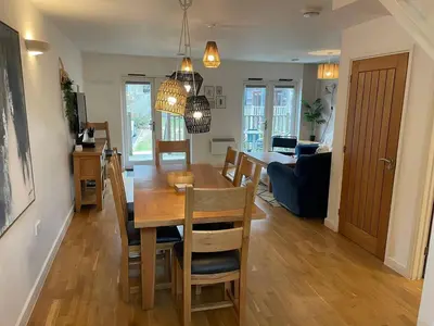 a dining room and living room with a table and chairs at House 6 Goldcroft - Walk to Beach & Village, Pet-friendly & hottub in Porthtowan