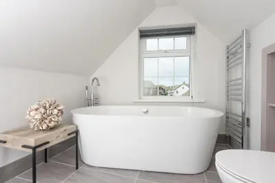 a white bath tub in a bathroom with a window at Beach Vista, harbourside in St Ives in St Ives