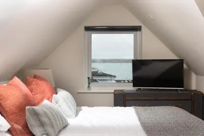 a bedroom with a bed with a television and a window at Beach Vista, harbourside in St Ives in St Ives