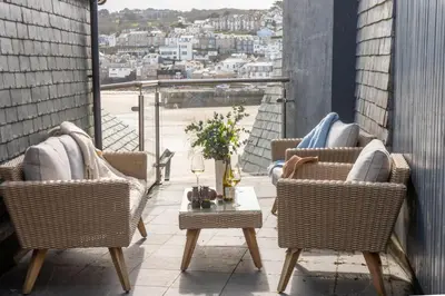 two chairs and a table on a balcony with a view at Beach Vista, harbourside in St Ives in St Ives