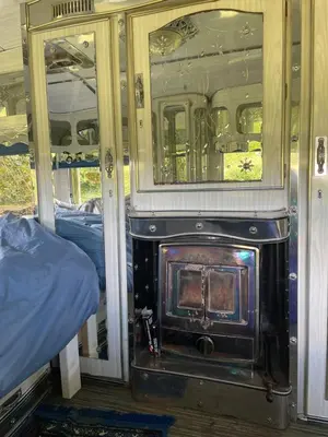 a room with a fireplace and a bed on a train at The Quarry Caravan in Falmouth