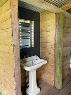 a bathroom with a white sink in a wooden wall at The Quarry Caravan in Falmouth
