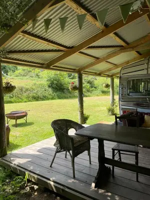 a wooden deck with a table and chairs under awning at The Quarry Caravan in Falmouth