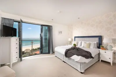 a bedroom with a large bed with a view of the ocean at Apartment 3 at Porthminster Mews in St Ives