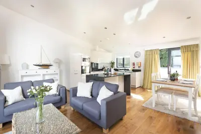 a living room with two blue couches and a kitchen at Apartment 3 at Porthminster Mews in St Ives