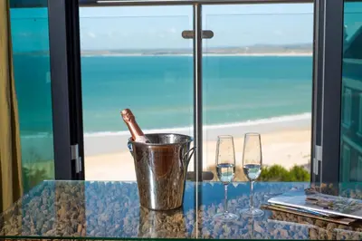 a table with two wine glasses and a bottle in a bucket at Apartment 3 at Porthminster Mews in St Ives