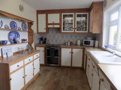 a kitchen with white cabinets and blue plates on the wall at Brookfield in Bude