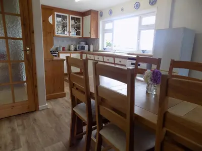 a kitchen with a table and chairs and a kitchen with a refrigerator at Brookfield in Bude