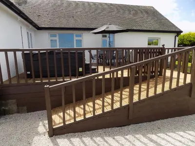 a wooden deck with an umbrella in front of a house at Brookfield in Bude