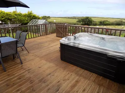 a hot tub on a deck with a table and an umbrella at Brookfield in Bude