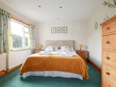 a bedroom with a bed with orange blanket and a window at Brookfield in Bude